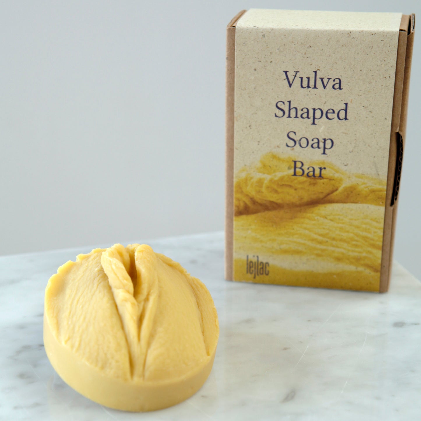 Seitenansicht der gelben Vulvaseife mit Hanf und Olivenöl für normale und trockene Haut mit nachhaltiger Verpackung aus Pappe und Graspapier
